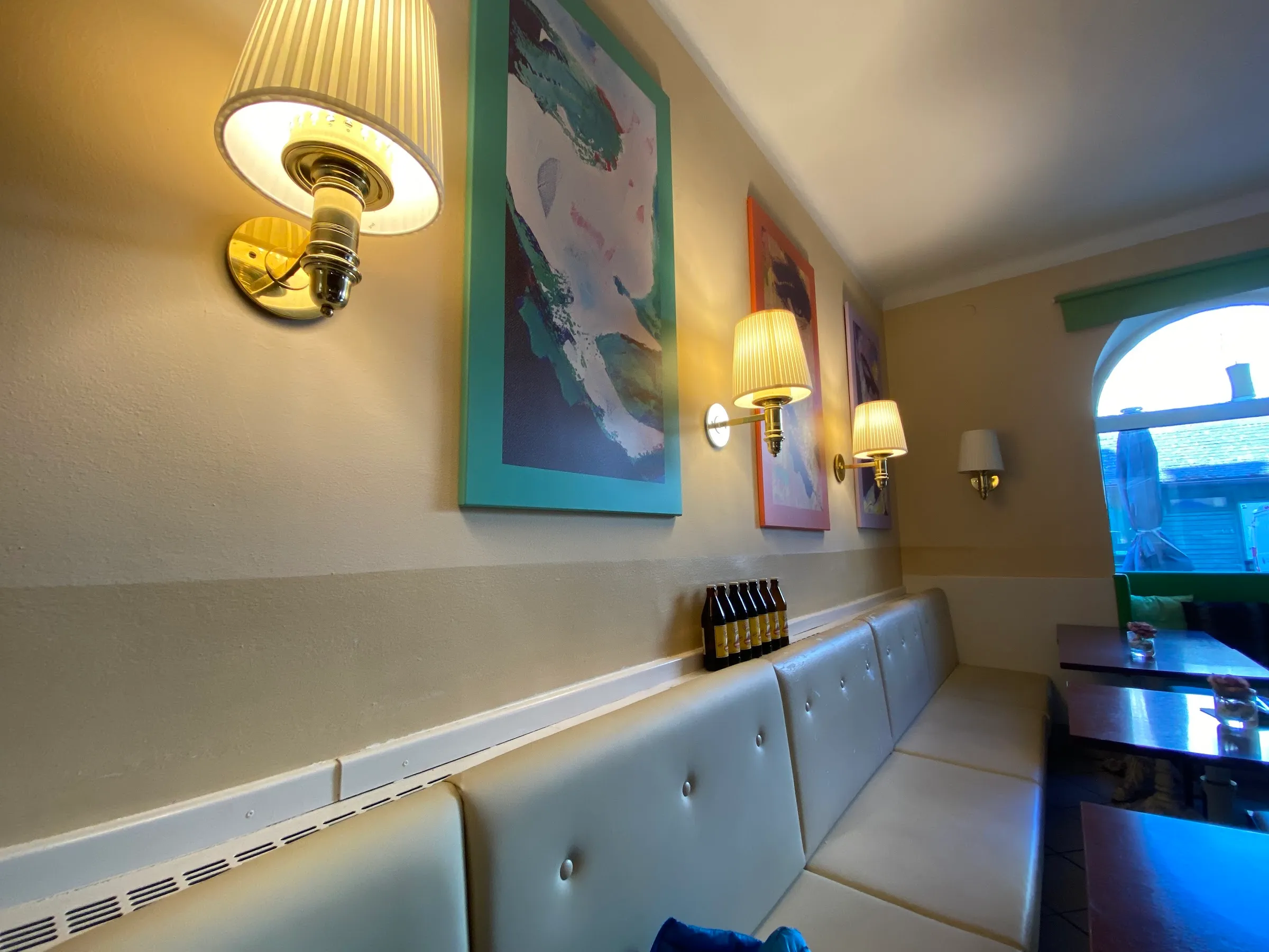 Cremefarbene Sitzbank unter Bildern und Messinglampen